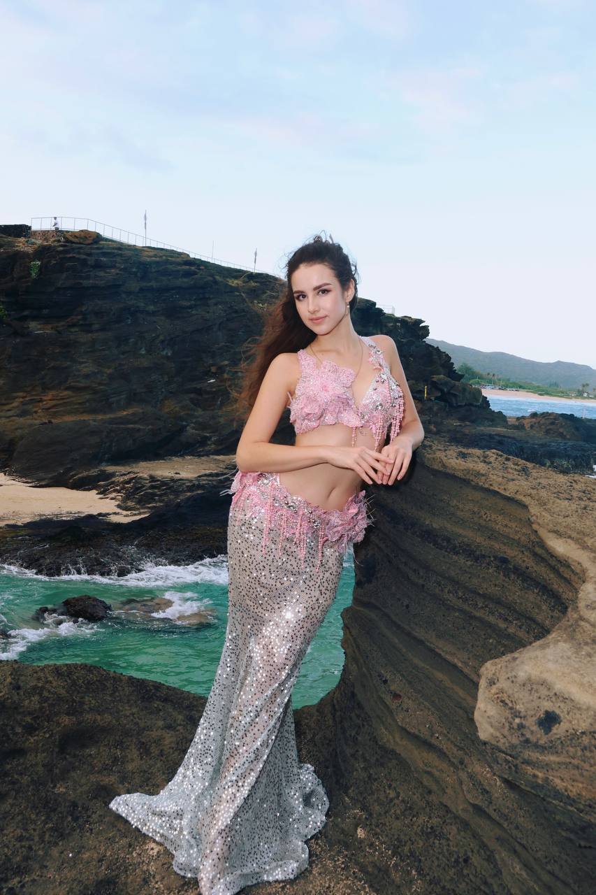 Angelina posing gracefully by the sea in a pearl-beaded costume